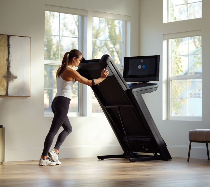 Nordic Track Commercial 2450 Treadmill with female folding it away.