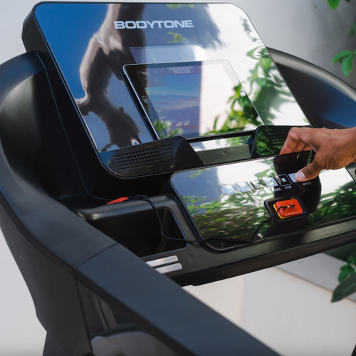 Console close up showing a person using a Smartphone app resting on the Bodytone DT21+ Treadmill LED tablet holder 