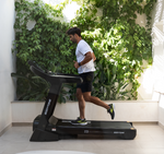 Person running on the Bodytone DT21+ Treadmill LED in a modern indoor setting with greenery