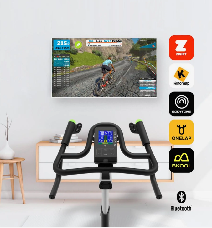 Bodytone Smart Bike V3 with screen displaying cycling route on TV and various app icons on a white wall.