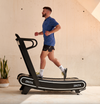 Side View of man running on a Bodytone ZROT4 Light Commercial Curved Treadmill in a home setting