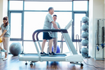 Dyaco Medical Physical Therapy Treadmill 4.0T in gym room with male patient walking on it with therapist standing at the side of the treadmill.