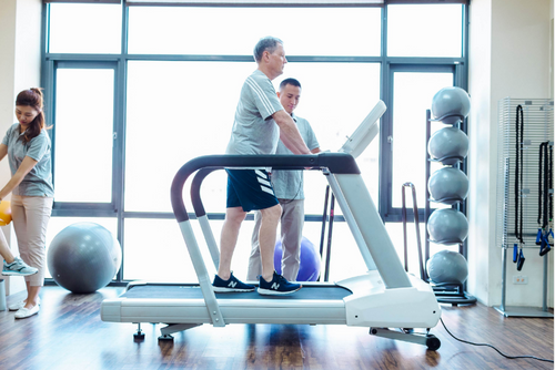Dyaco Medical Physical Therapy Treadmill 4.0T in gym room with male patient walking on it with therapist standing at the side of the treadmill.