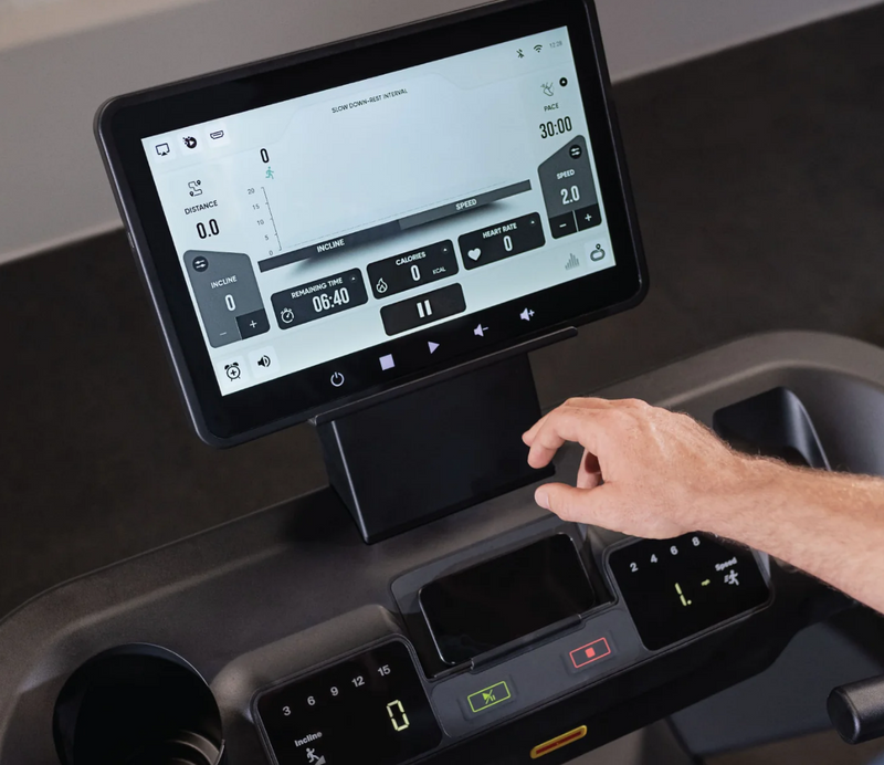 Person interacting with Inspire Fitness T7S treadmill control panel featuring a digital display.