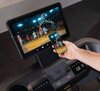 Person using a smartphone to control a tablet displaying a basketball game on  Inspire Fitness T7S treadmill
