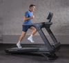 Man running on Inspire Fitness T7S treadmill against a brick wall.