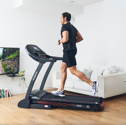 Man running on a Bodytone Active Run LED treadmill in a living room setting