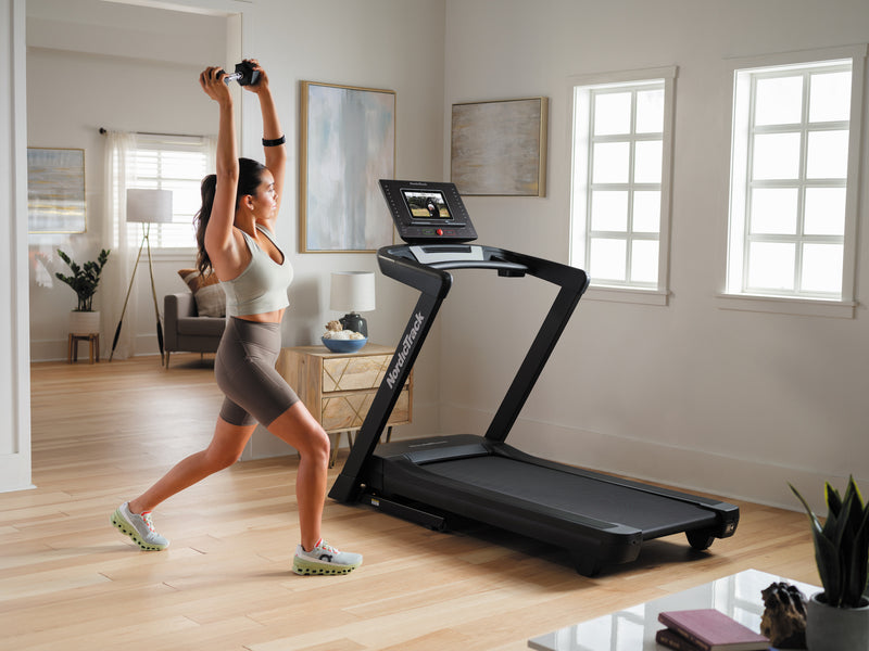 Nordic Track EXP 10i Treadmill in room with female exercising at the side of the treadmill