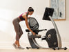 Nordic Track R35 Recumbent Bike. An image taken from a side angle showing a female altering the position of the seat.