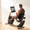 Nordic Track R35 Recumbent Bike. Side view of a male following a programme whilst working out. The bike is in a domestic setting.