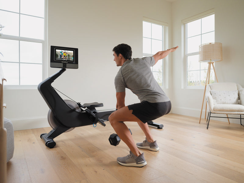 Nordic Track RW700 Rower. An image of a male standing at the side of the rower following a dumbell excercise being screened on the rower console.