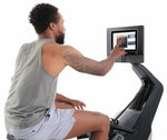 Nordic Track RW700 Rower. Male sitting on the machine using the touch screen console to select a programme.