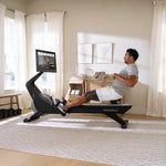 Nordic Track RW900 Rower. Image of a male working out on his rowing machine in a home setting.