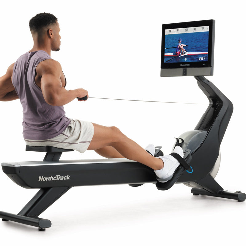Nordic Track RW900 Rower. Image of  a male rowing. The image is taken from the back of the machine at an angle.