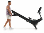 Nordic Track RW900 Rower. An image of a male demonstrating how to move the rower using  with the help of the transport wheels at the front of the machine.