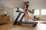 A person running on a NordicTrack Commercial 1750 Treadmill in a home environment.
