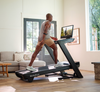 A person exercising on a NordicTrack Commercial 2450 Treadmill with a male focusing on the treadmill's 24-inch HD touchscreen.