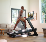A person exercising on a NordicTrack Commercial 2450 Treadmill with a male focusing on the treadmill's 24-inch HD touchscreen.