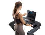 NordicTrack Commercial 2450 Treadmill with woman pressing the buttons on the console against white background