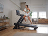 NordicTrack Commercial LE Treadmill side view of woman running on machine in room setting.