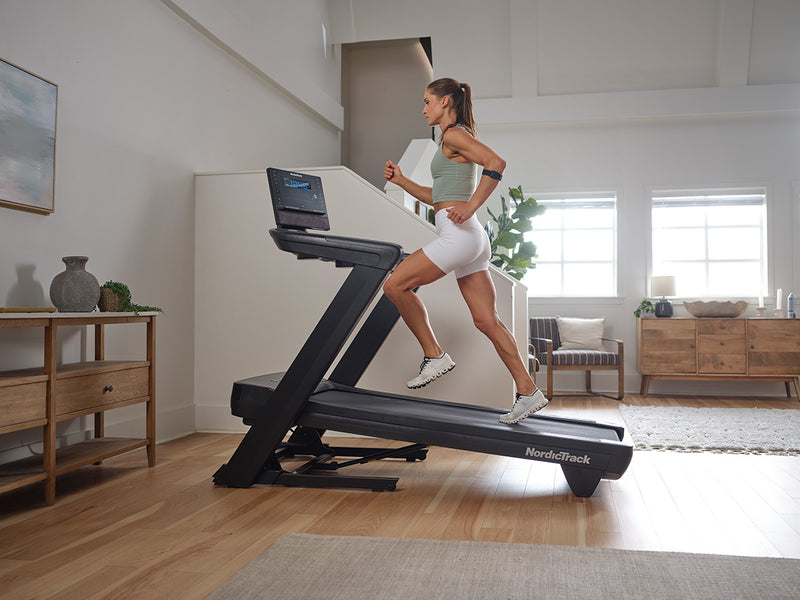 NordicTrack Commercial LE Treadmill side view of woman running on machine in room setting.