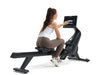NordicTrack RW300 Rowing machine with woman sitting on rower using console with white background