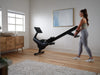 NordicTrack RW300 being moved on its transport wheels by woman in room