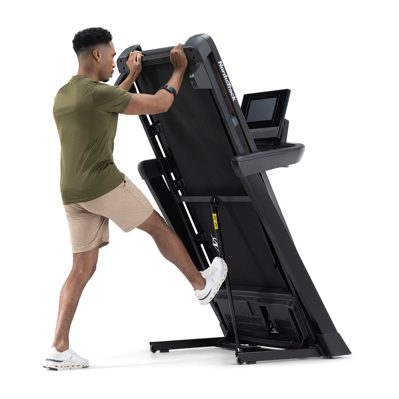 NordicTrack T10 Treadmill with man showing how to unfold it using his foot.