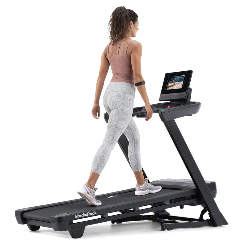 NordicTrack T10 Treadmill slightly elevated with woman walking on it against white background
