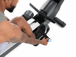 Nordic Track RW700 Rower. Image of male sitting on the rower demonstrating how to use the foot straps on the footplates.