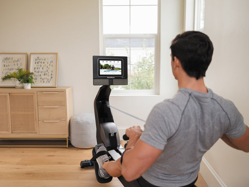 Nordic Track RW700 Rower. Man rowing and looking at the console whilst in a programme.