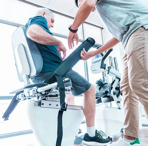 Dyaco Medical Rehabilitation Recumbent Seated Stepper 7.0S in gym room with therapist helping patient into the seat.