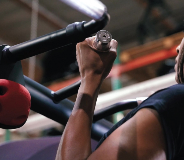 Person using a gym machine with a close-up of their arm holding onto the handle.