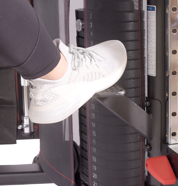 Person stepping onto a weight stack with white sneakers on a gym machine.