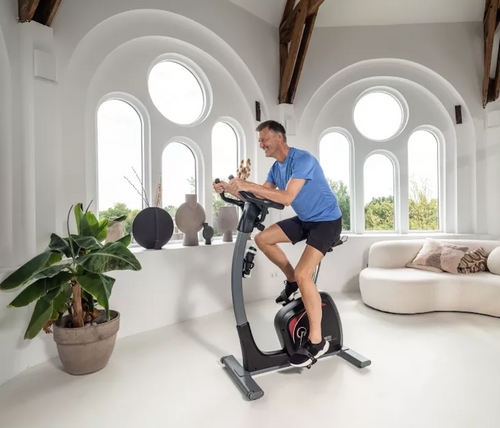 Flow Fitness DHT 2500i Upright Bike with male rider in room setting
