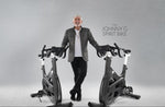 Ikage of a male standing in between two Spirit Johnny G Bikes.  Fitness Options, Online Gym Equipment Supplier and Nottinghamshire Showroom